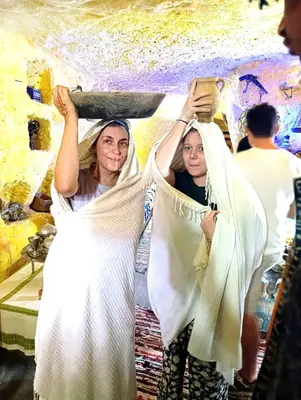 two women are holding up white sheets at Grotte Thami in Bhalil