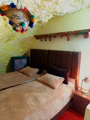 a bedroom with two beds and a wall covered in snow at Grotte Thami in Bhalil