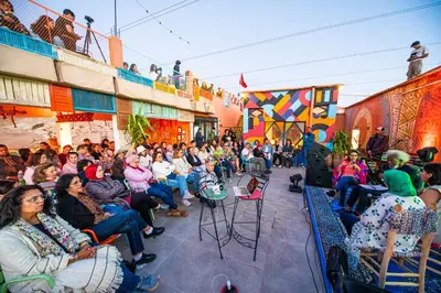a crowd of people sitting in front of a stage at taman'art space in Aït Ben Haddou