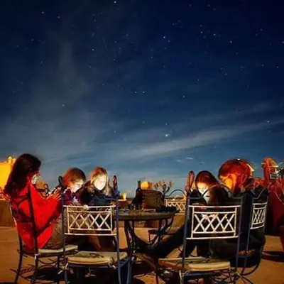 a group of people sitting at a table at the beach at Kasbah Azalay Merzouga takojt in Merzouga
