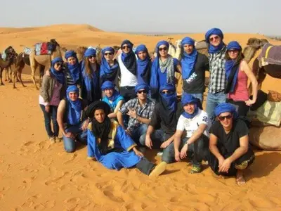 a group of people posing for a picture in the desert at Kasbah Azalay Merzouga takojt in Merzouga