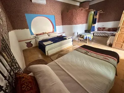 a bedroom with two beds and a mirror at Kasbah Azalay Merzouga takojt in Merzouga