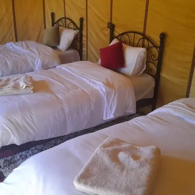 a room with two beds with white sheets and a red pillow at Luxury trek desert camp in Merzouga