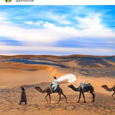 a group of people riding camels in the desert at Luxury trek desert camp in Merzouga