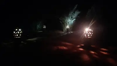 two cars with their lights on in the dark at Luxury trek desert camp in Merzouga