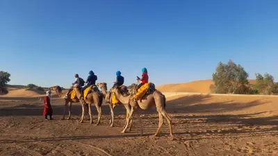 a group of people on camels in the desert at Luxury trek desert camp in Merzouga