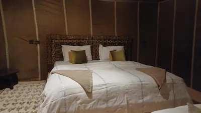 a bedroom with a large bed with white sheets and pillows at Luxury trek desert camp in Merzouga