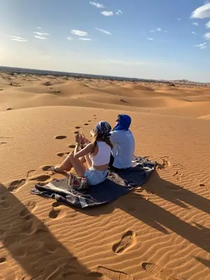 a man and a woman sitting in the desert at Luxury trek desert camp in Merzouga