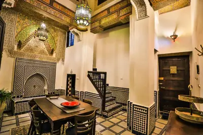 a room with a table and chairs and a staircase at Dar Chez Khadija in Fès