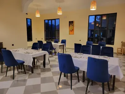 a dining room with tables and blue chairs at Le Domaine M in Ouzoud