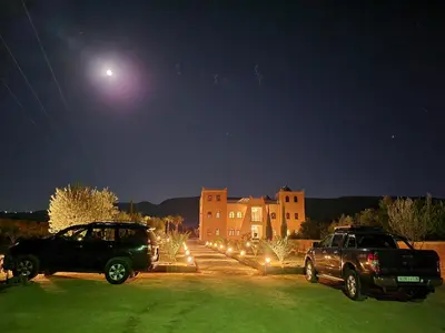 two trucks parked in front of a building at night at Le Domaine M in Ouzoud