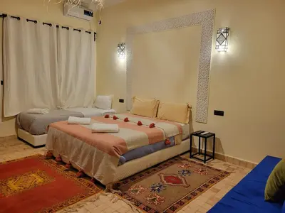a bedroom with two beds and a large window at Le Domaine M in Ouzoud