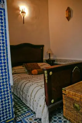 a bedroom with a bed with a wooden head board at dar lmallouki in Fès