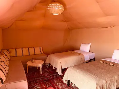 a room with two beds and a couch and a table at Merzouga Glamping Camp in Merzouga