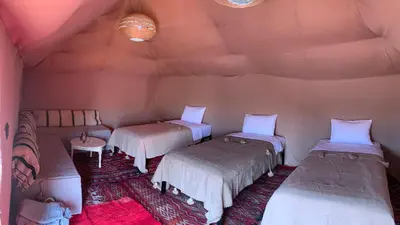 a room with three beds and two chairs in it at Merzouga Glamping Camp in Merzouga