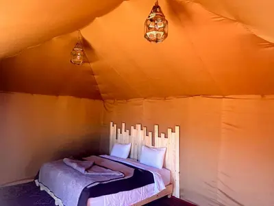 a bedroom with a bed in a tent at Merzouga Glamping Camp in Merzouga