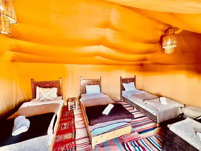 a room with three beds in a tent at Merzouga Glamping Camp in Merzouga