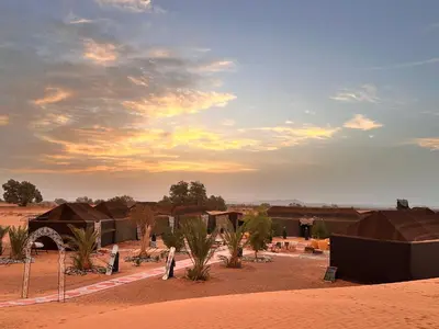 a group of houses in the middle of a desert at Merzouga Glamping Camp in Merzouga