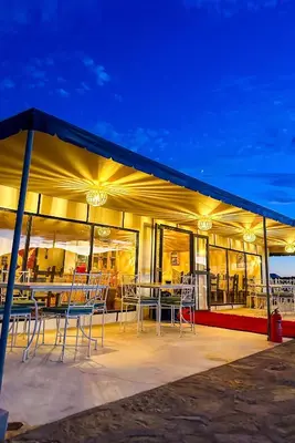 a building with tables and chairs on a patio at Starlit Luxury Camp in Merzouga