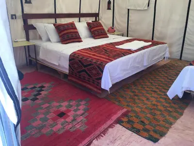 a bedroom with a bed in a tent with a rug at Merzouga Camel's & Camp in Merzouga