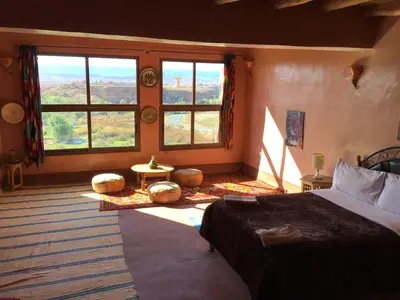 a bedroom with a bed and a large window at Kasbah Itran in Kalaat MGouna