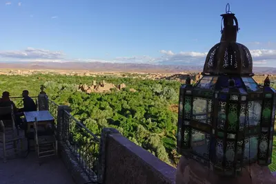 a group of people sitting at a table on a balcony looking at a view at Kasbah Itran in Kalaat MGouna