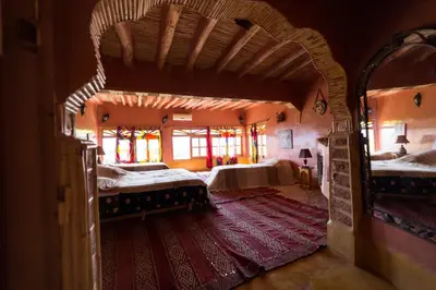a large bedroom with two beds and a red rug at Kasbah Itran in Kalaat MGouna