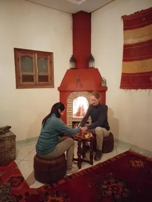 a man and a woman sitting in front of a fireplace at Gîte Ait lmaalam chez Ahmed in Skoura