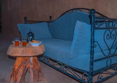a blue bed with a table with two glasses on it at Gîte Ait lmaalam chez Ahmed in Skoura