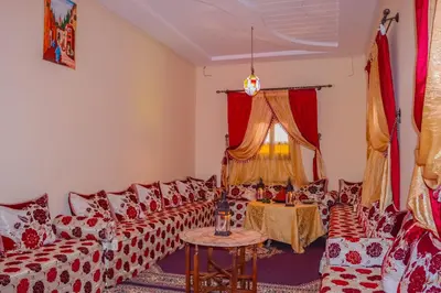 a living room with red and white couches and a table at Gîte Ait lmaalam chez Ahmed in Skoura