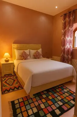 a bedroom with a large white bed and a rug at Grotte Salwa in Aït Ben Haddou