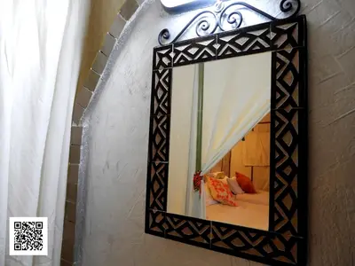 a mirror with a black frame hanging on a wall at Luxury Desert Camp in Merzouga in Tisserdmine
