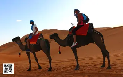 two people riding on the backs of camels in the desert at Luxury Desert Camp in Merzouga in Tisserdmine