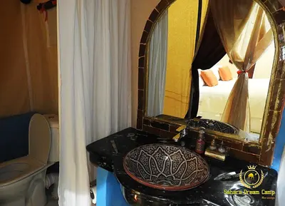 a bathroom with a sink and a mirror and a bed at Luxury Desert Camp in Merzouga in Tisserdmine