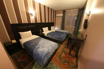 a hotel room with two beds and a mirror at Hotel Akouas in Meknès