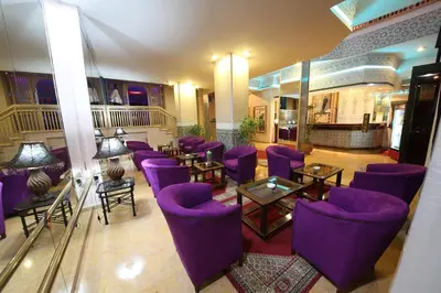 a hotel lobby with purple chairs and tables at Hotel Akouas in Meknès