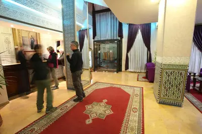 a group of people standing in a lobby with a red rug at Hotel Akouas in Meknès