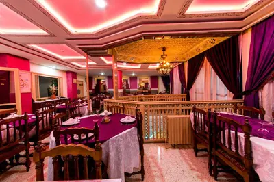 a restaurant with tables and chairs in a room at Hotel Akouas in Meknès