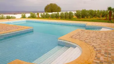 a large swimming pool with blue tiles on the ground at Hotel Angle Atlas & Spa in Tit n Ziza