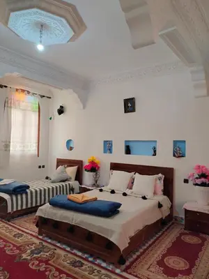 two beds in a room with white walls at Riad dar Ahlam in Aït Baha