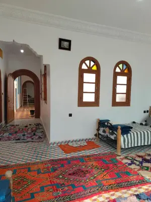 a room with a bed and two windows and a rug at Riad dar Ahlam in Aït Baha