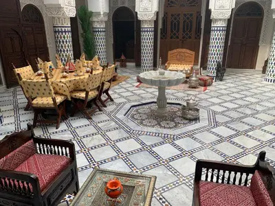 a dining room with a table and chairs and a fountain at Riad Palais Marouane in Meknès