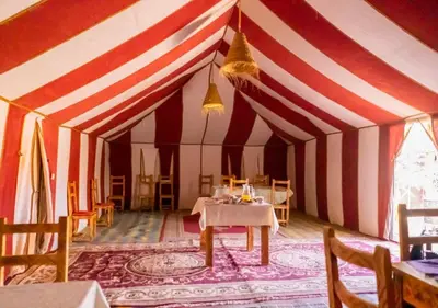 a dining room with a red and white striped tent at Desert Life Camp in Merzouga