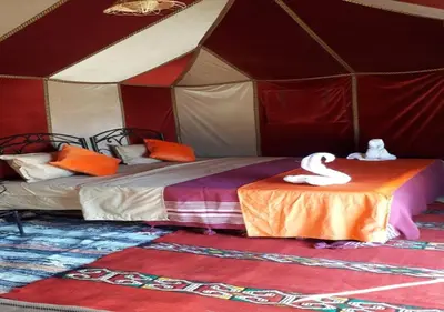a tent with two beds and a swan on a table at Desert Life Camp in Merzouga