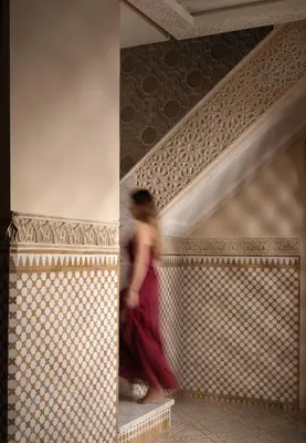 a woman in a red dress walking down a staircase at Palais De Fès Suites & Spa in Fès