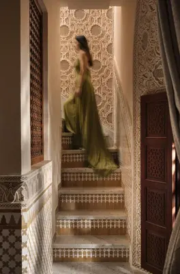 a woman in a green dress walking down stairs at Palais De Fès Suites & Spa in Fès