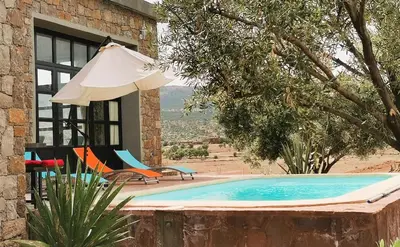 a house with a swimming pool and an umbrella at Soo Bin in Bine el Ouidane
