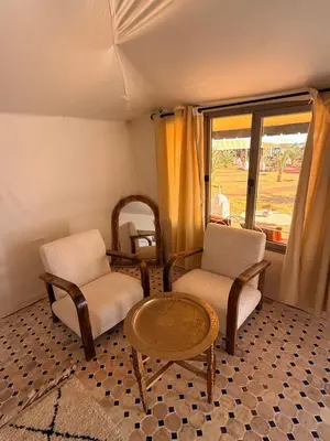 a room with two chairs and a table and a window at Aladdin merzouga camp in Merzouga