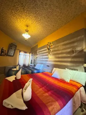 a bedroom with a large bed with a colorful blanket at AUBERGE KSAR MERZOUGA in Merzouga