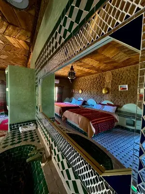 a large room with two beds and a bathroom at AUBERGE KSAR MERZOUGA in Merzouga